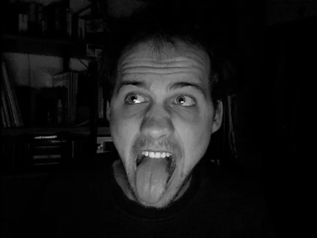 2007 — Portrait mit herausgestreckter Zunge in der Dunkelheit